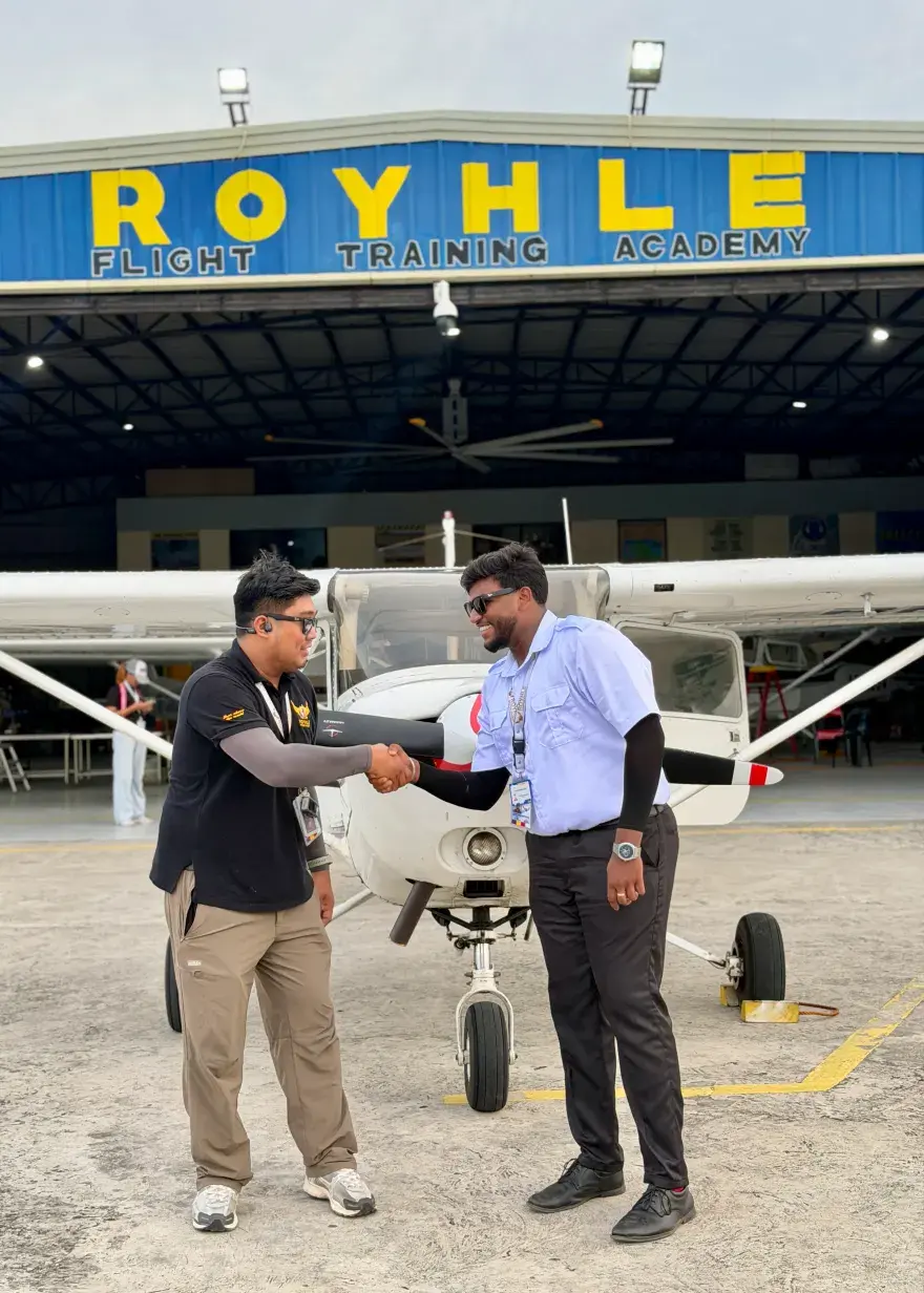 A student pilot shaking hands with an instructor in front of a Cessna trainer